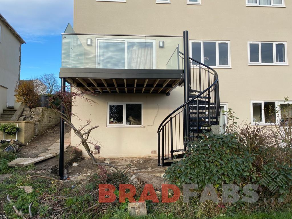 Balcony with spiral staircase, channel system infinity glass with stainless steel top rail and privacy screen to one side by Bradfabs 