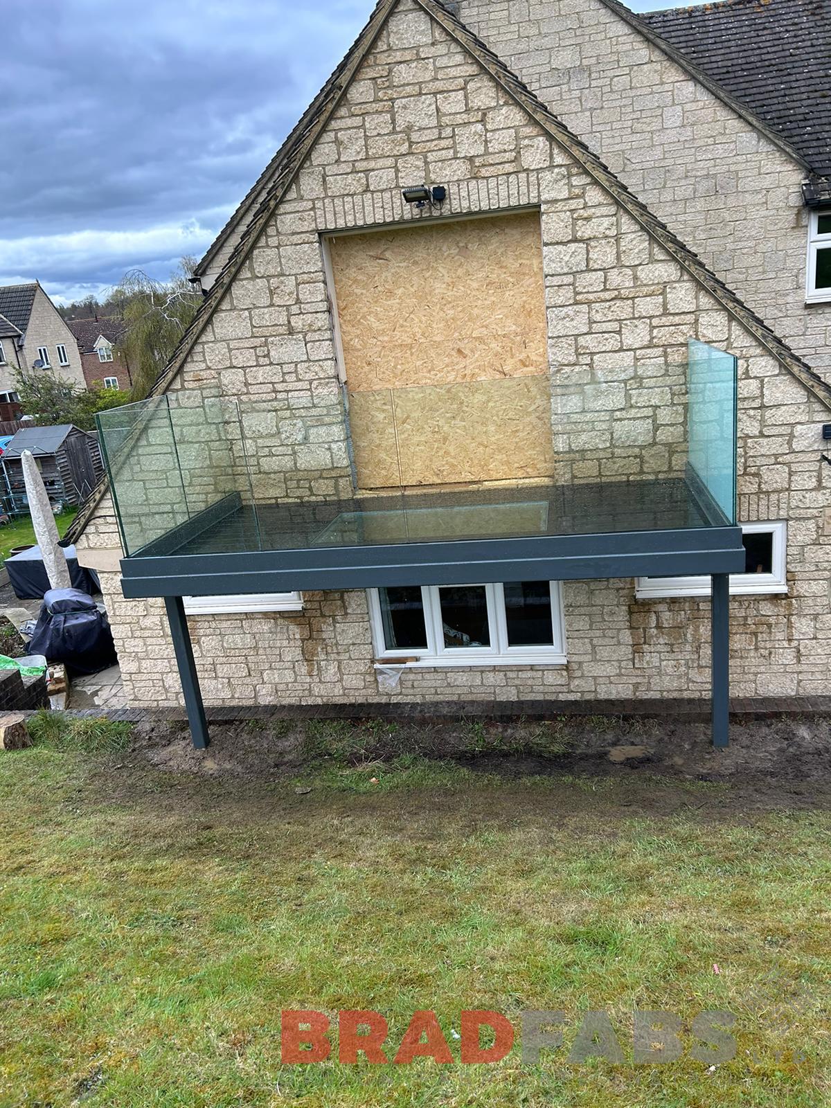 Balcony with privacy screen to one side and clear glass panel in centre of the decking by Bradfabs