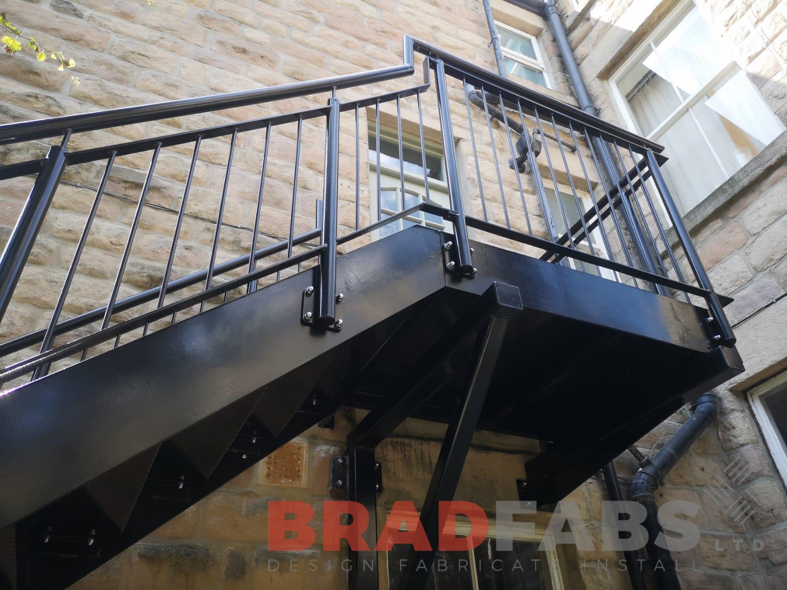 Small landing at the top of external straight staircase in mild steel, galvanised and powder coated black at customers choice with vertical bar balustrade by Bradfabs 