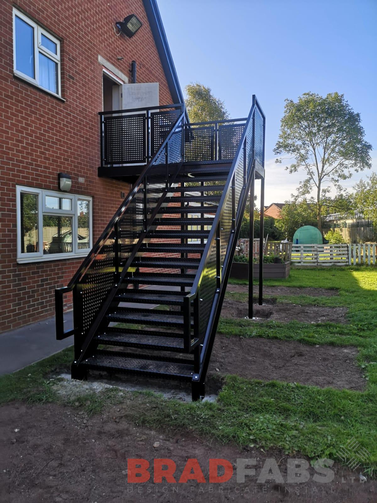 View from the bottom of this commercial properties new bespoke straight fire escape with perforated balustrade and powder coated black by Bradfabs 