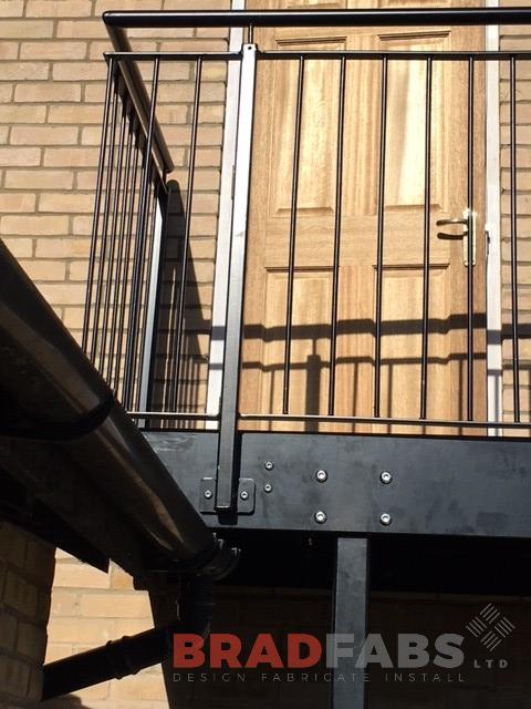 Mild steel, galvanised and powder coated black vertical bar balustrade on the landing at the top of an external staircase by Bradfabs 