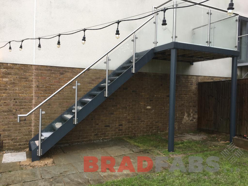 fire escape for a domestic property, manufactured in mild steel, galvanised and powder coated with stainless steel and glass balustrade, complete with durbar treads and composite decking on landings by Bradfabs 
