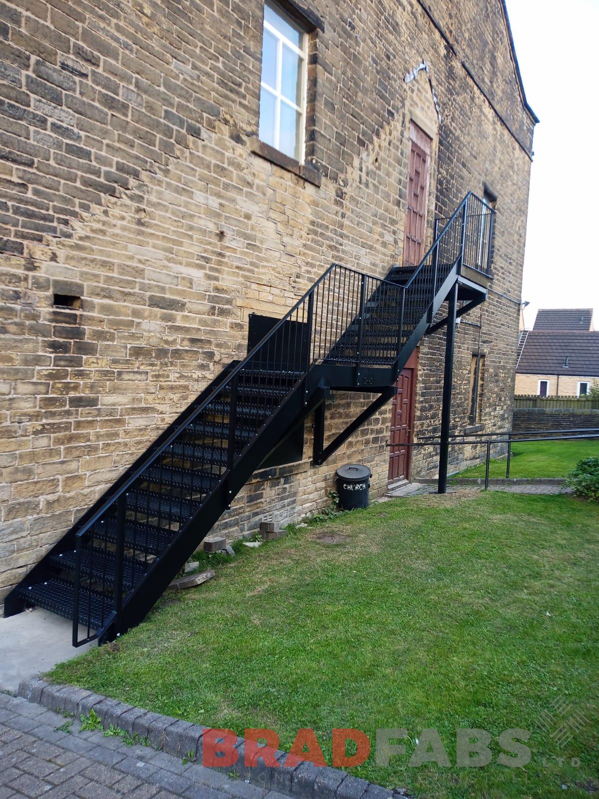 Large external staircase with top and mid landing, vertical bar balustrade and durbar treads all manufactured in mild steel, galvanised and powder coated black by bradfabs 