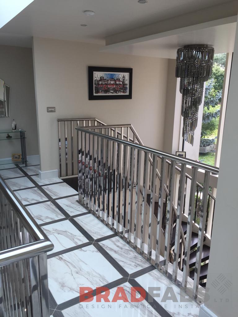 Bespoke helix staircase with polished stainless steel vertical bar balustrade and stainless steel top rail, open treads and landing balustrade to match the staircase balustrade by Bradfabs 