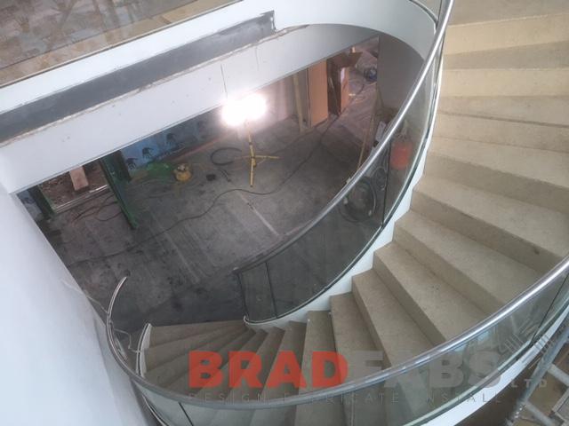 Bespoke internal helix staircase, with infinity glass balustrade and stainless steel top rail by Bradfabs 