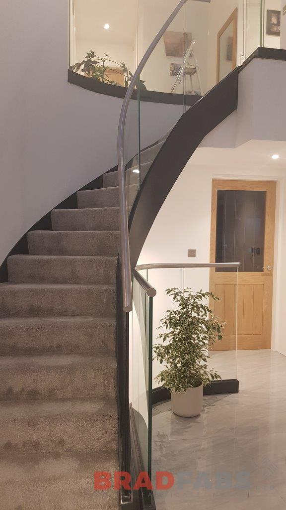 Bespoke steel frame helix staircase with infinity glass and tubular stainless steel handrail by bradfabs 