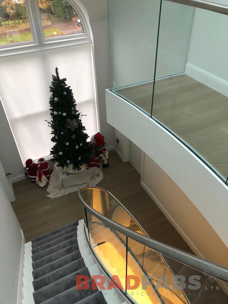 Bespoke helical staircase for a domestic property, with infinity glass balustrade and stainless steel top rail by bradfabs 