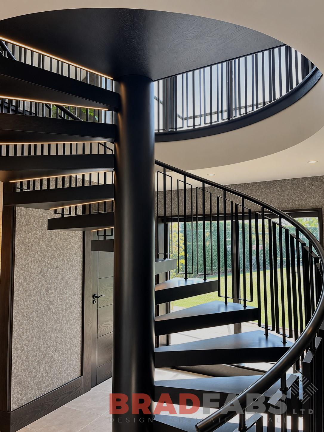 Modern spiral staircase with oak stained timber treads, powder coated in brown.